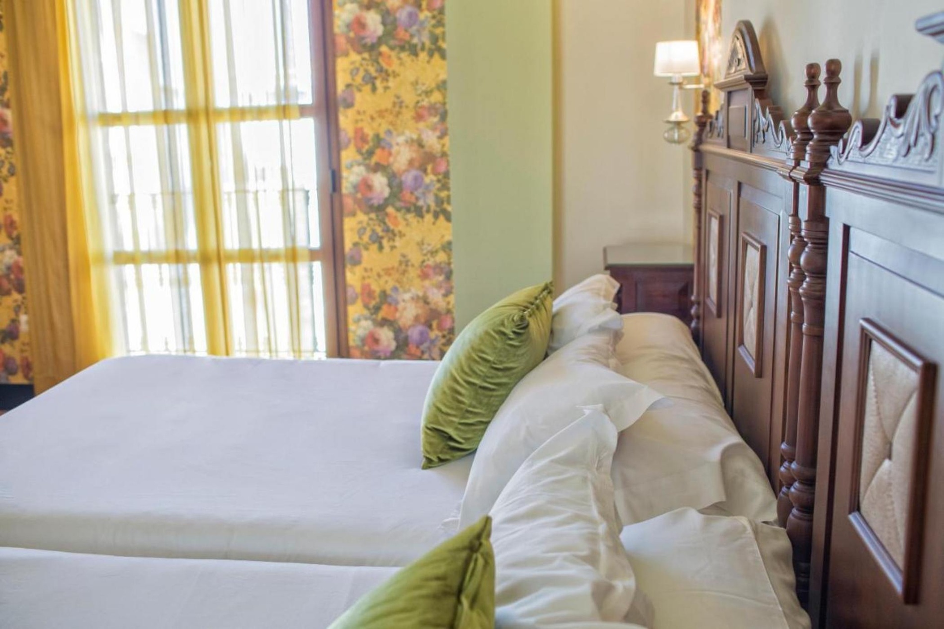 una habitación con dos camas y una ventana con cortinas florales