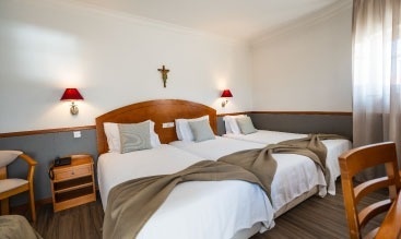 una habitación de hotel con dos camas y una cruz en la pared .