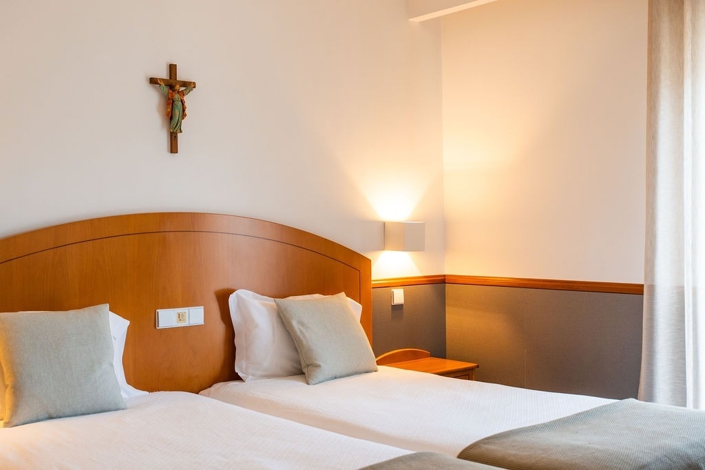 una habitación con dos camas y una cruz en la pared