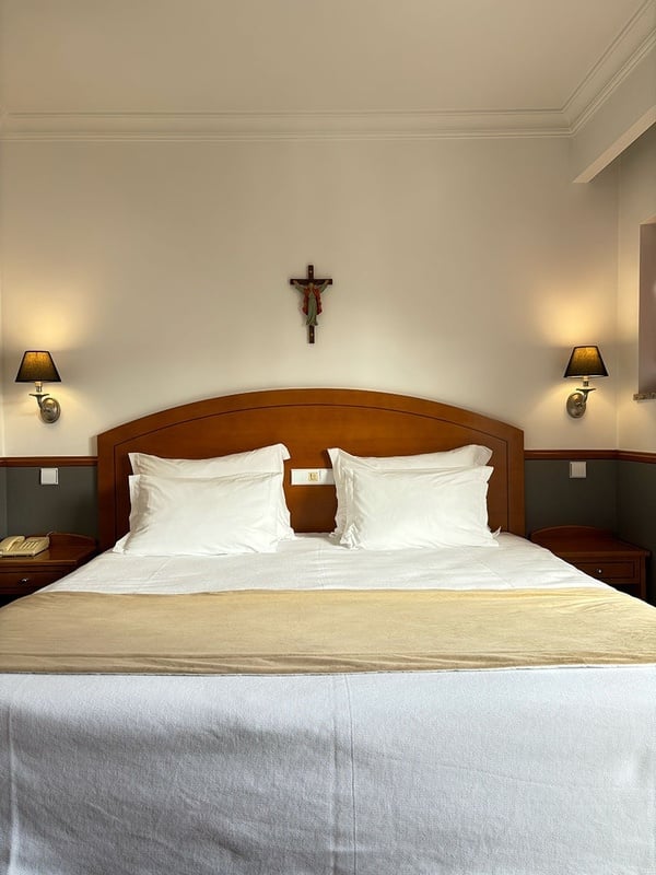 a hotel room with a cross on the wall above the bed