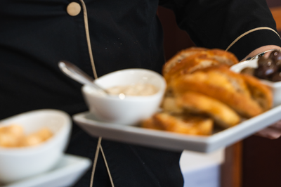 un camarero sostiene una bandeja blanca llena de comida