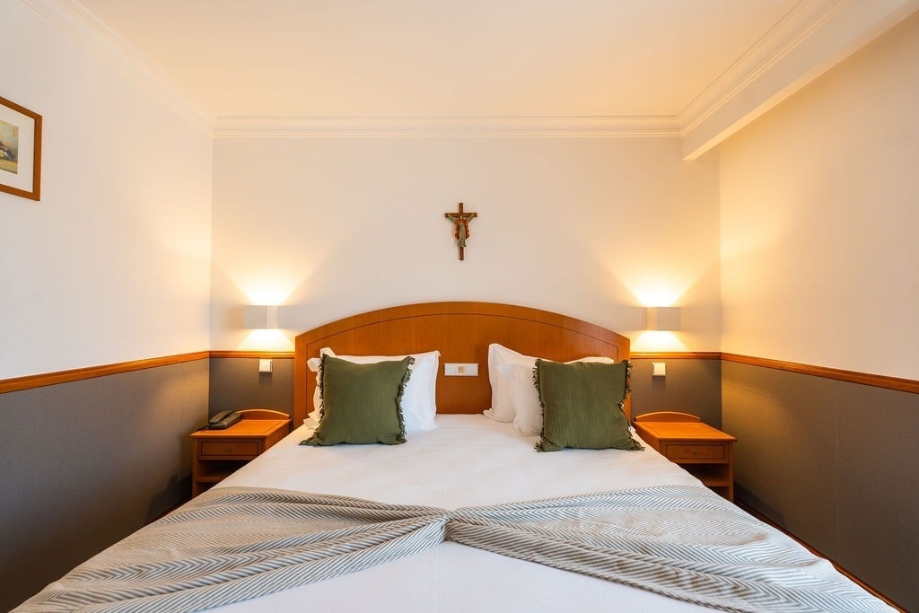 una habitación con una cama y una cruz en la pared