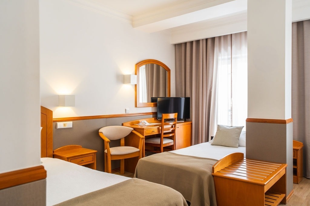 una habitación de hotel con dos camas , un escritorio y una televisión