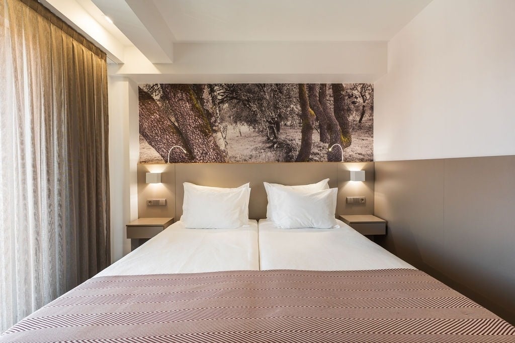 um quarto com uma cama e uma pintura de árvores na parede
