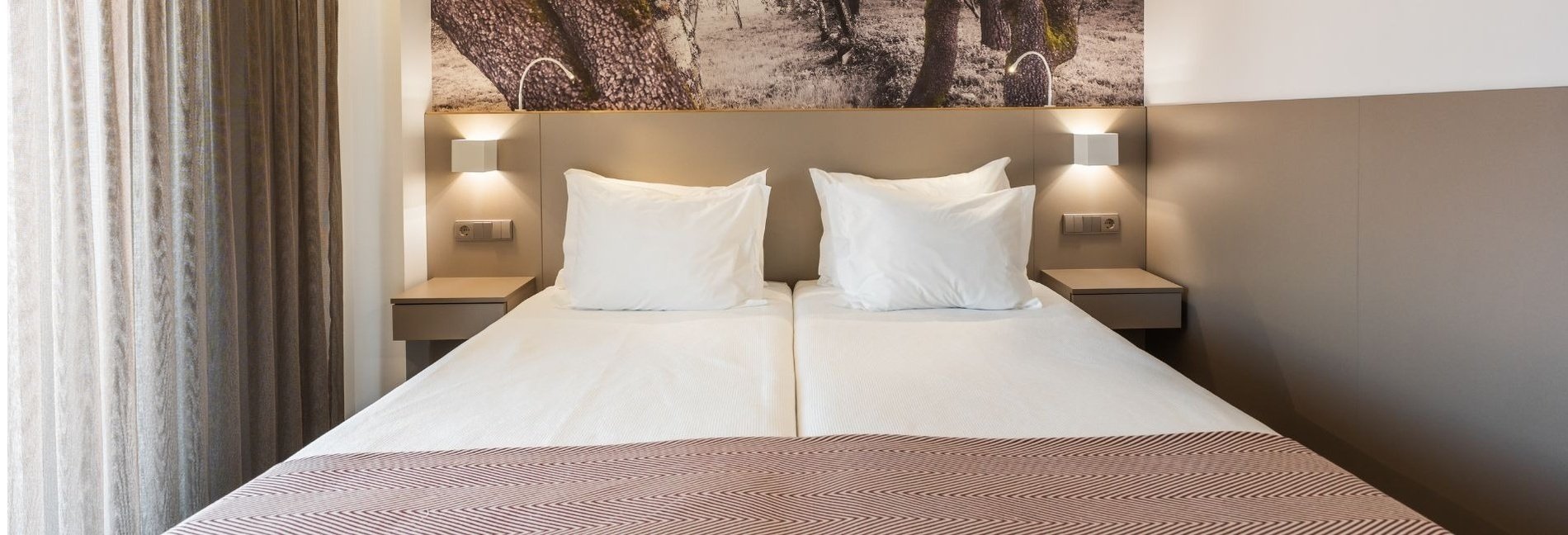 a bed with a picture of trees on the wall behind it