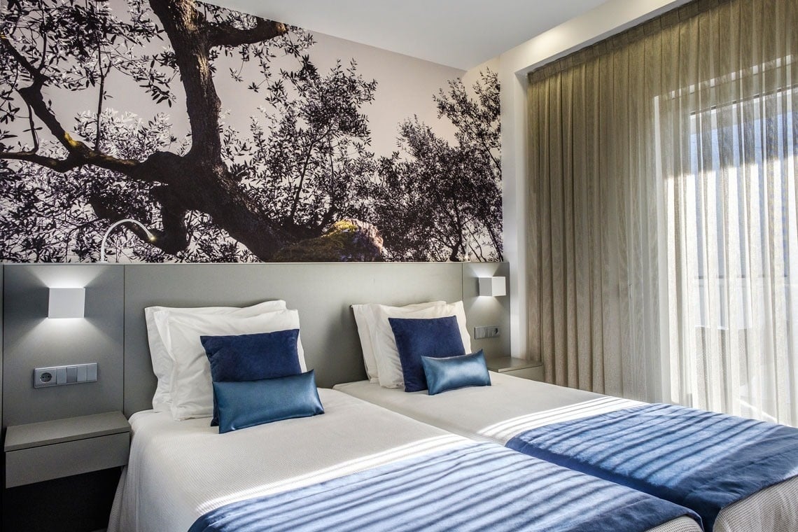 a hotel room with two beds and a picture of trees on the wall