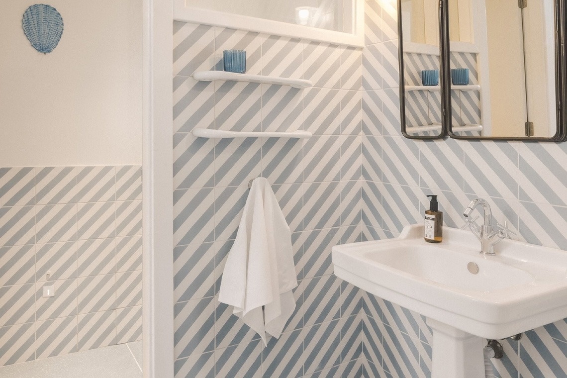 Baño moderno Satocan: The Salmar con azulejos de espiga, lavabo blanco y toalla.
