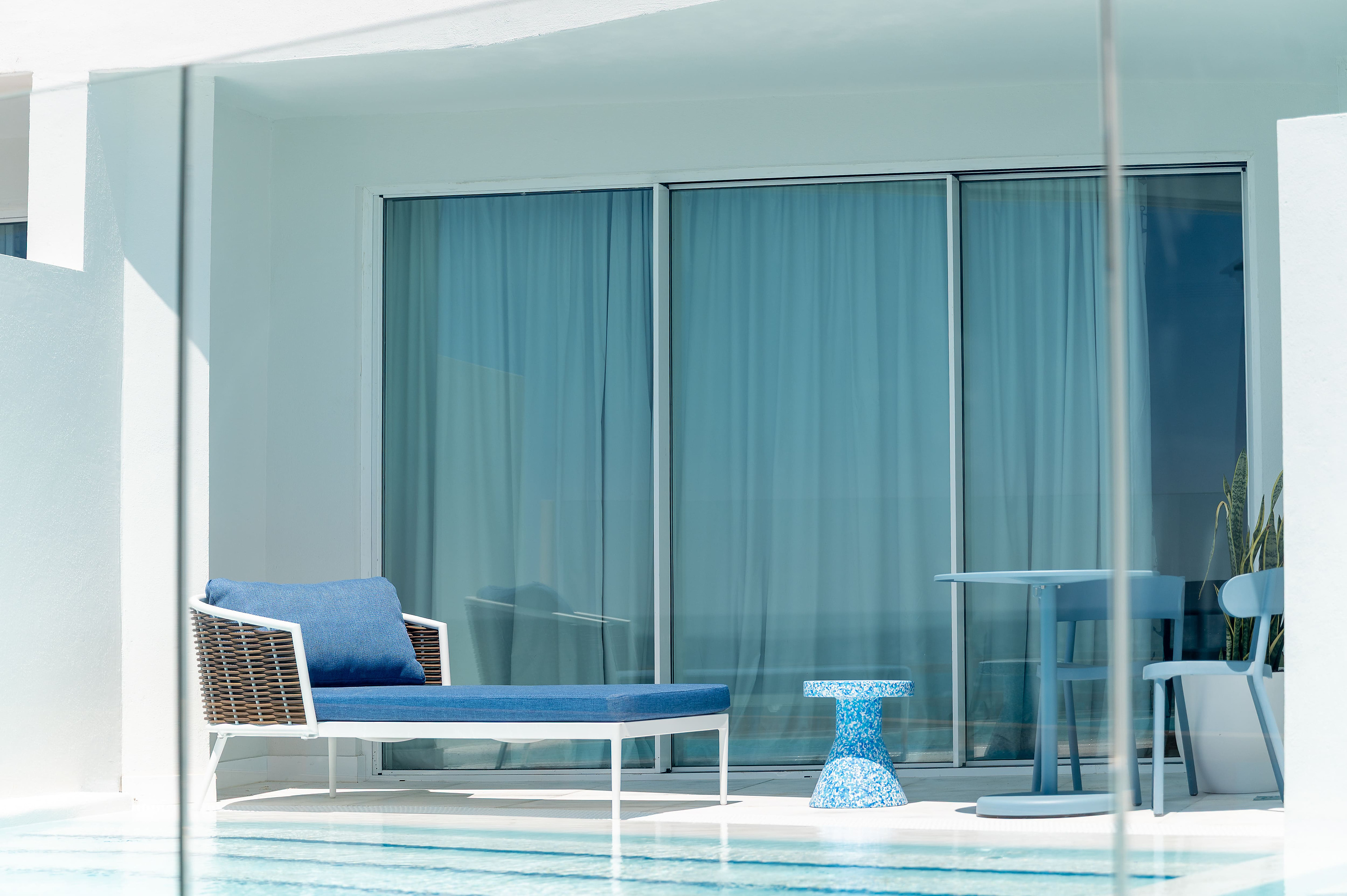 Tumbona azul con almohada en balcón de hotel junto a la piscina. Satocan: The Salmar