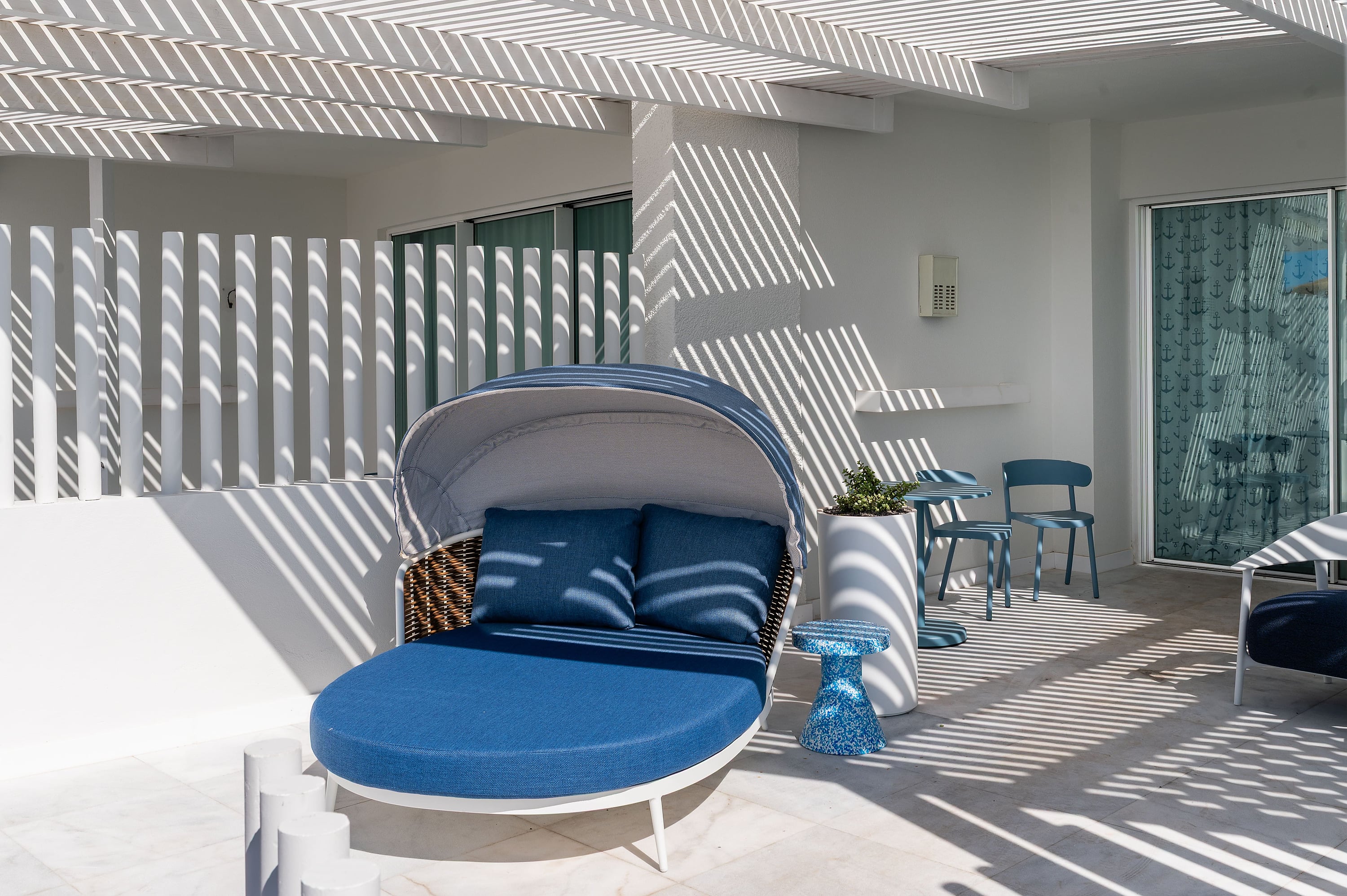 Satocan: The Salmar: Tumbona azul y mesa en terraza de hotel con sombra de pérgola.