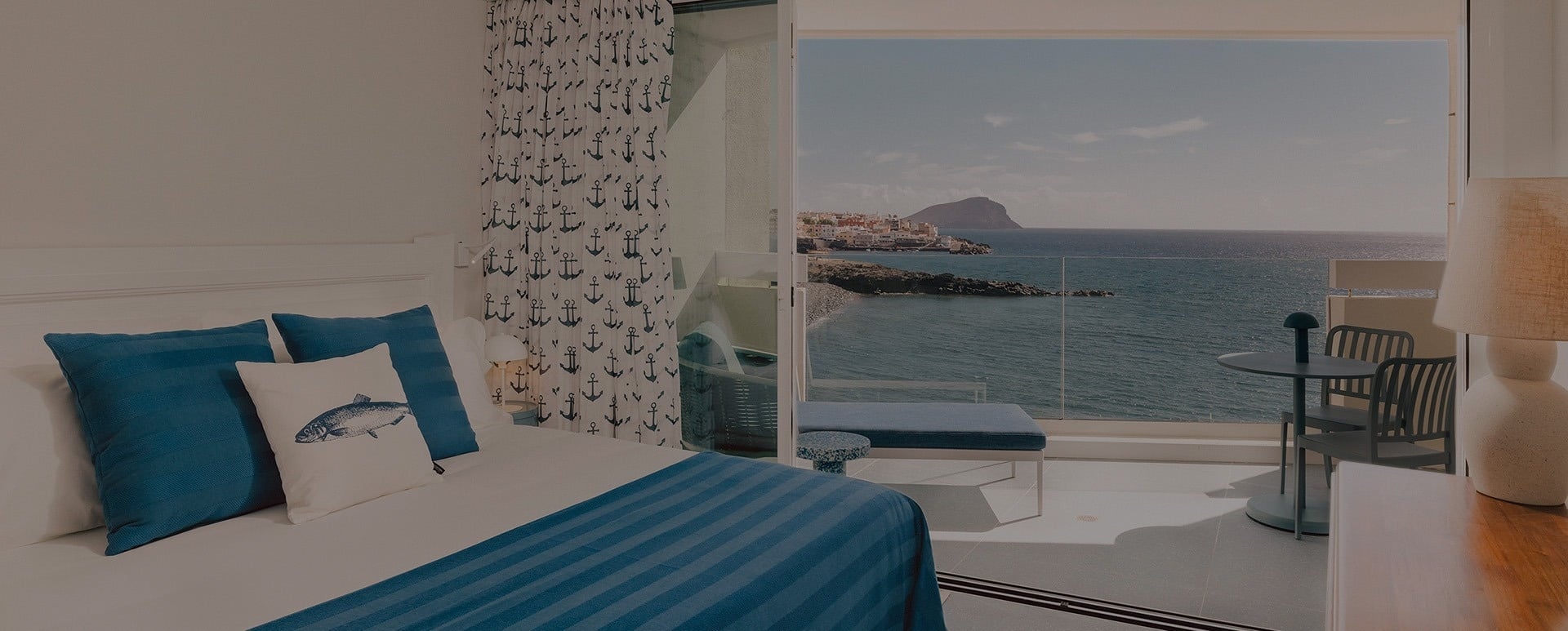 Una habitación con temática náutica y balcón ofrece vistas al mar y a un pueblo costero.