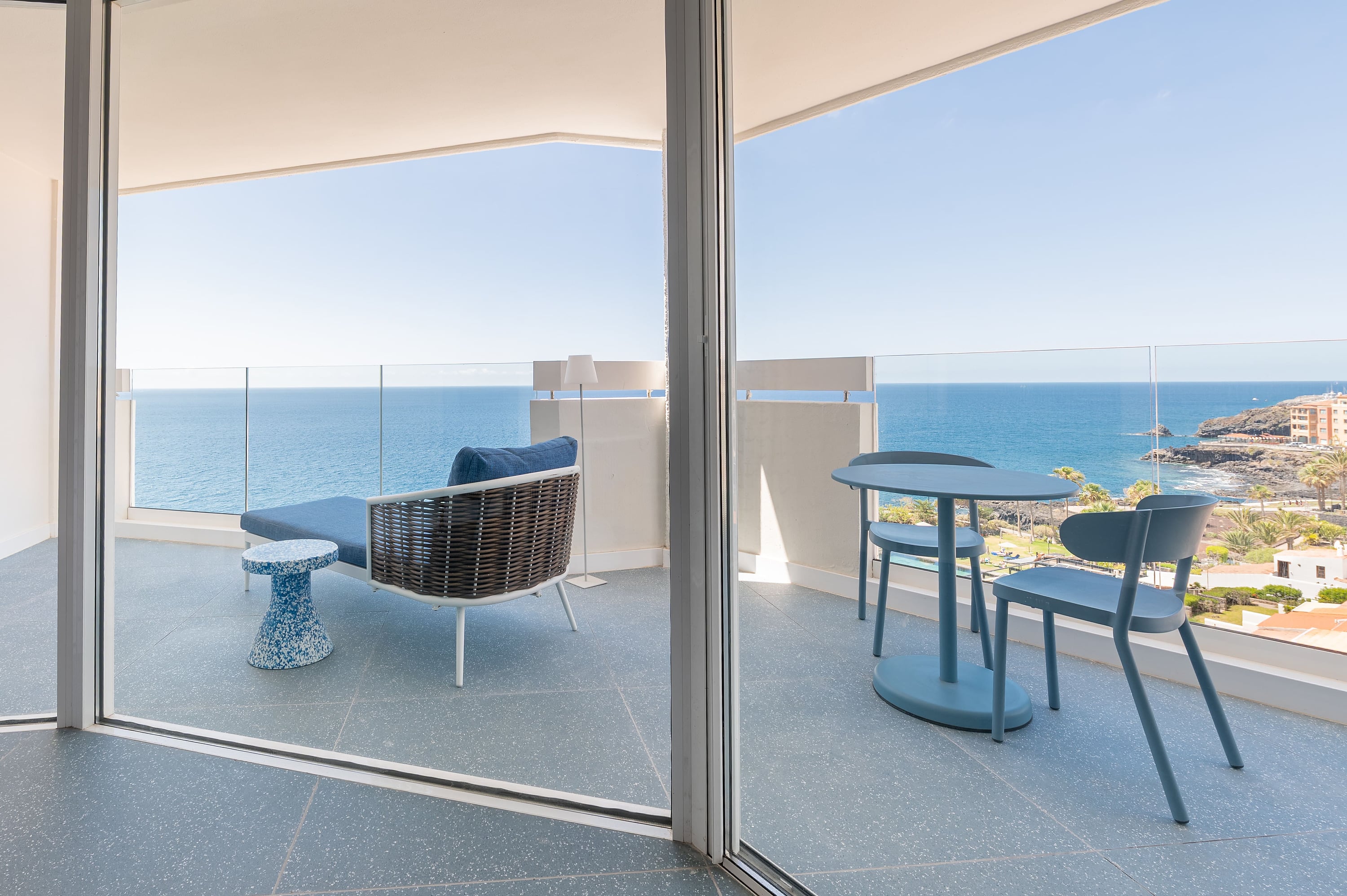 Terraza con vista al mar, chaise longue azul y mesa con sillas. Satocan: The Salmar