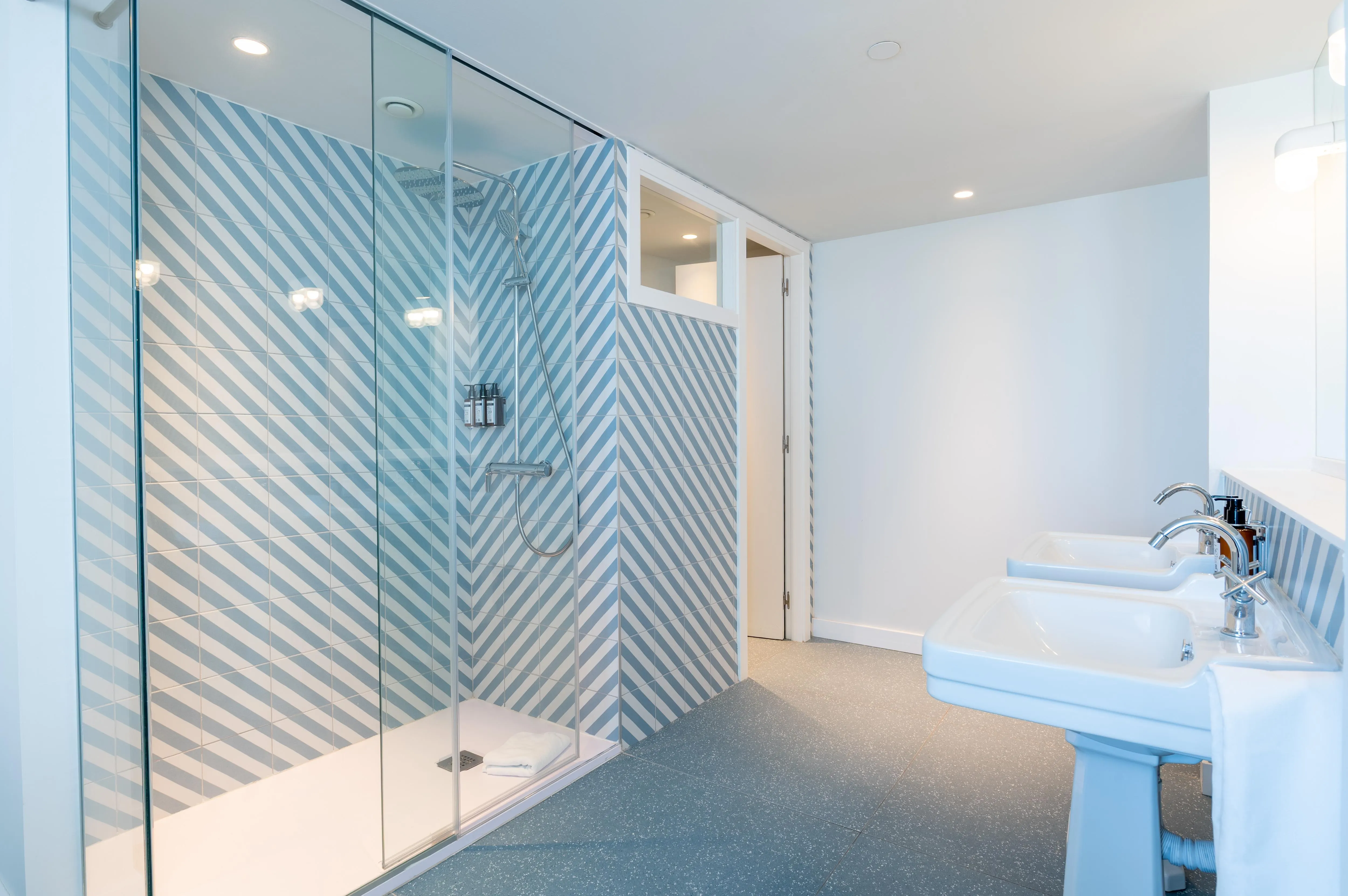 Baño moderno con ducha de azulejos en espiga azul en hotel The Salmar