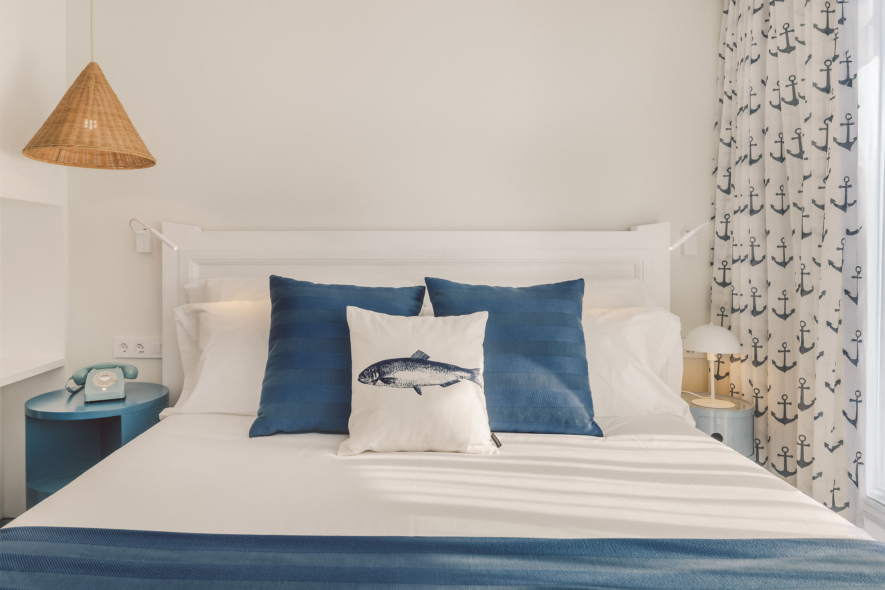 Cama acogedora con almohadas temáticas de Satocan: The Salmar y cortinas náuticas.