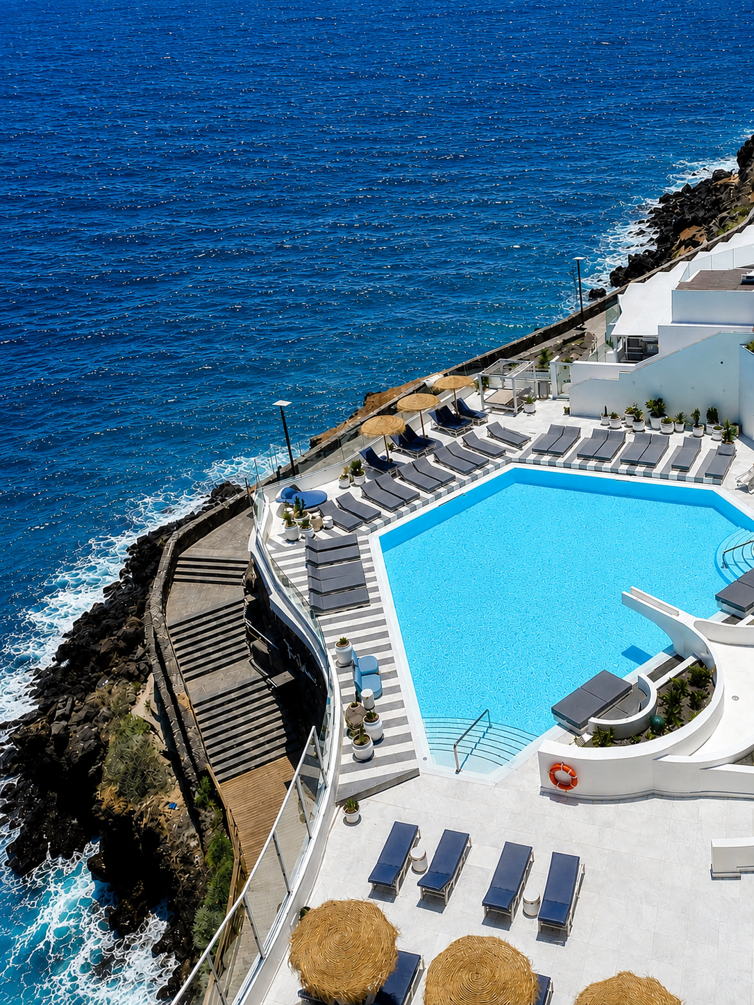 Tumbonas modernas junto a piscina infinita con vista al mar, ideal para Satocan: The Salmar.