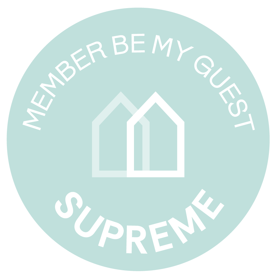 Un logo circular aguamarina, con dos contornos de casas blancas en el centro, muestra el texto "MEMBER BE MY GUEST" en la parte superior curva y "SUPREME" en la inferior.