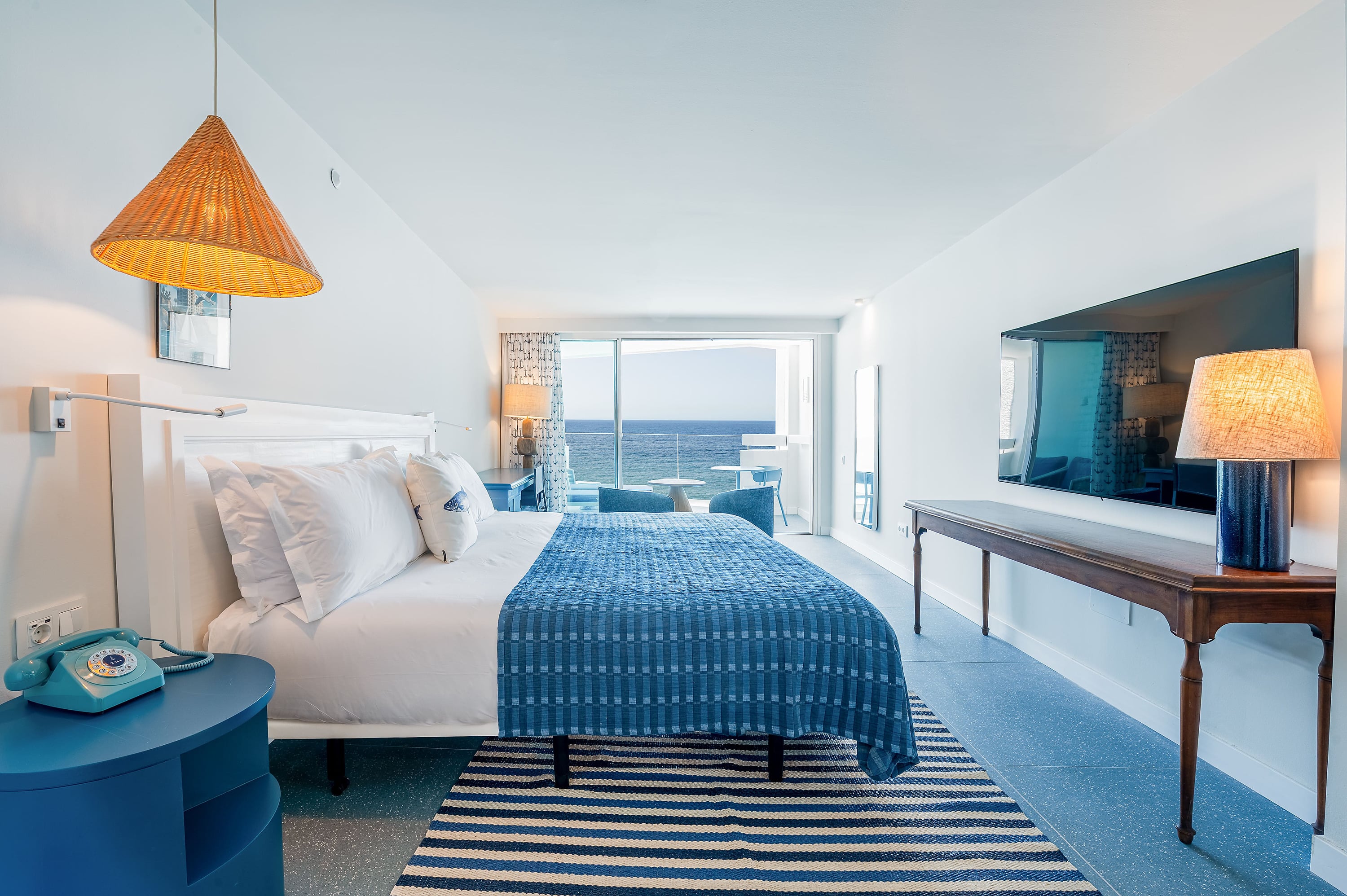Satocan: The Salmar: Habitación de hotel con vista al mar, cama ##KEYWORD## azul, lámpara de mimbre y balcón.
