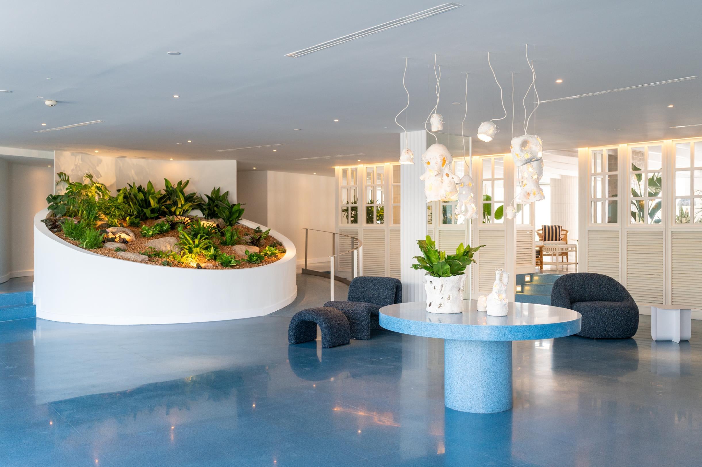 Recepción moderna con diseño de plantas y mesa azul, ideal para Satocan: The Salmar.
