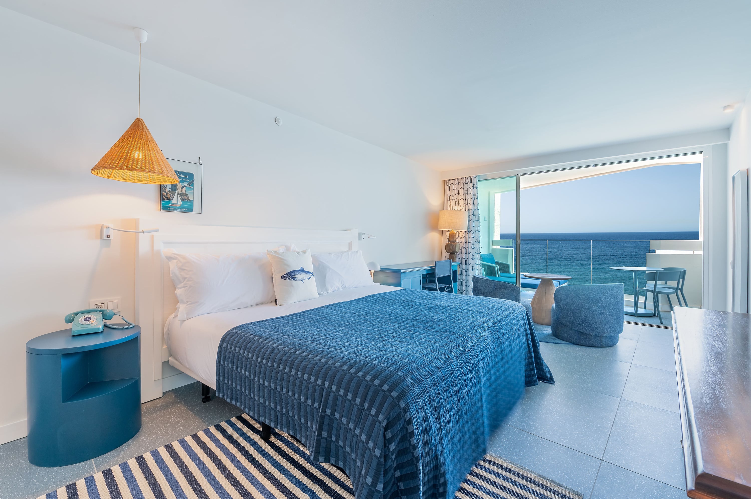 Habitación hotelera con vista al mar, cama azul, Satocan: The Salmar y balcón.