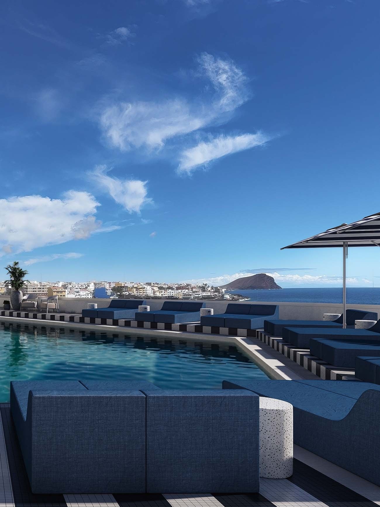 Designer pool at The Salmar hotel in Tenerife, with spacious blue daybeds, black and white striped floors, and unobstructed views of the El Médano coast and the ocean.