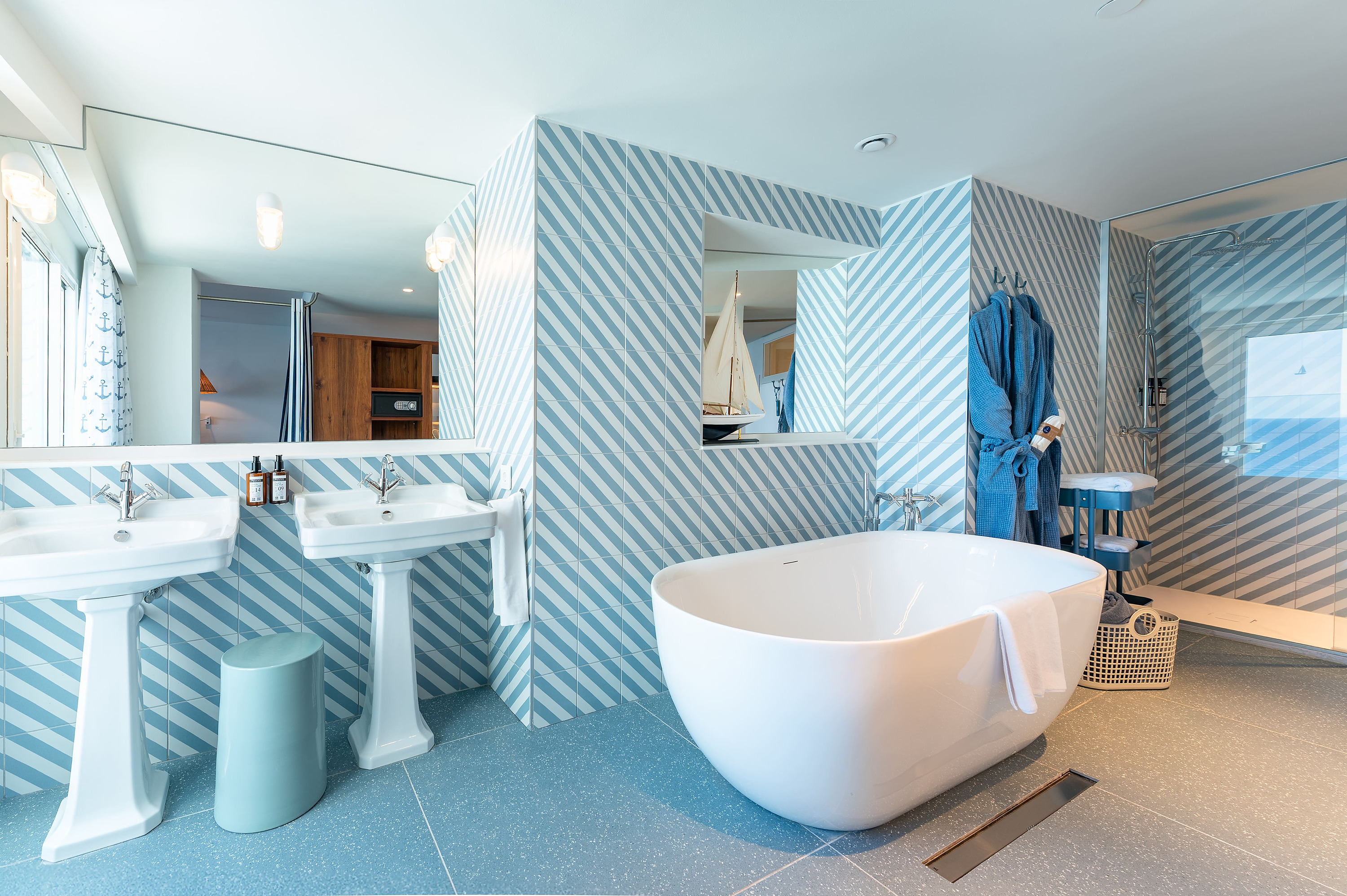 Elegante baño con bañera independiente, dos lavabos y ducha, decorado con azulejos náuticos y toallas azules. Satocan: The Salmar