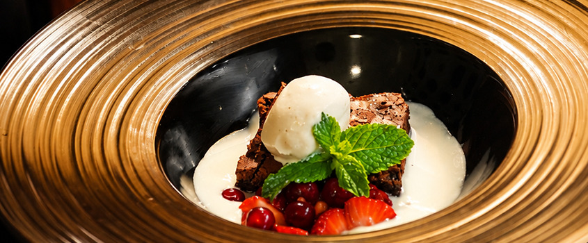 Gourmet chocolate brownie with vanilla ice cream and fresh berries, served in a unique wooden bowl. Satocan: The Salmar