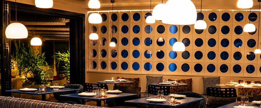 Interior of a modern restaurant with blue tables, elegant lighting, and patterned walls, perfect for a Satocan: The Salmar stay.