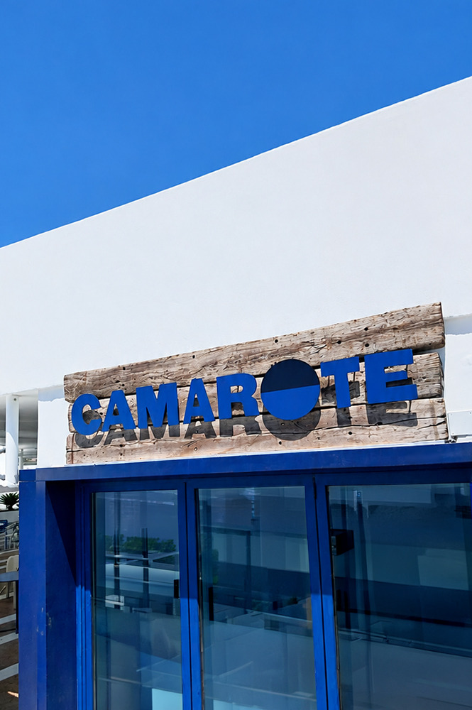 Camarote Satocan: The Salmar: Rustic wood sign with blue lettering above a modern blue and glass hotel entrance.