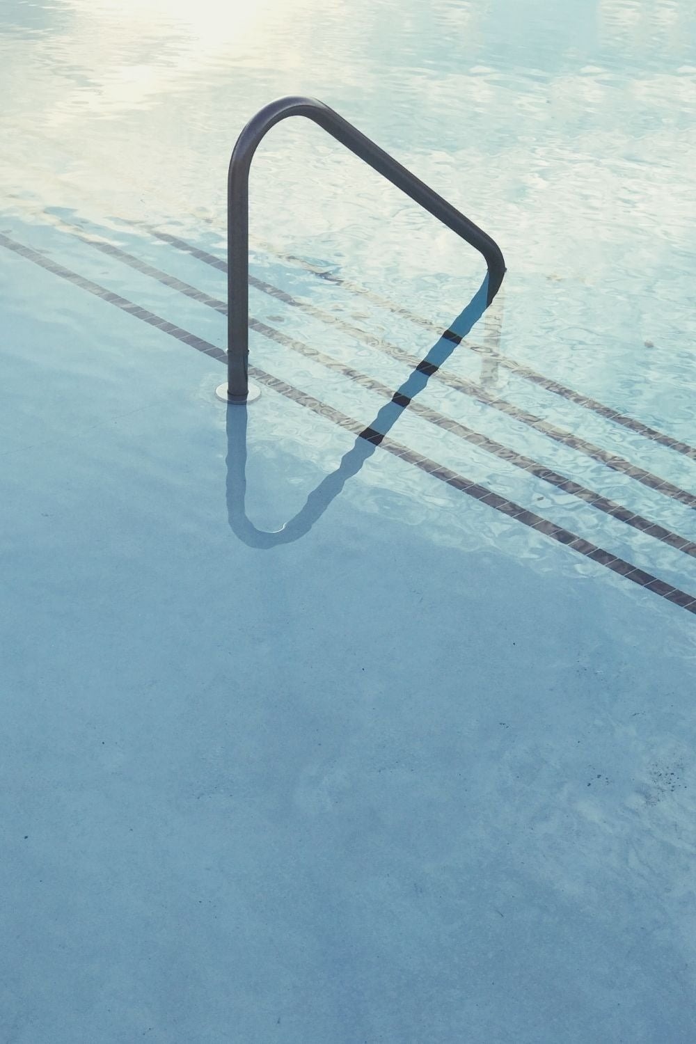 Una terraza moderna con una tumbona azul y una mesa auxiliar, ofrece una vista panorámica del vasto océano bajo un cielo despejado.