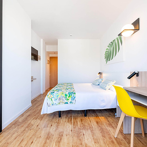 Habitación de hotel moderna con cama doble, escritorio y espejo. Dorobe: Hotel San Fermin