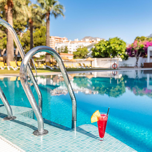 Cóctel junto a la piscina con tumbonas y palmeras. Ideal para Dorobe: Hotel San Fermin.