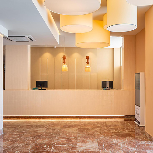 Recepción del hotel con decoración moderna, luces colgantes y suelo de mármol. Dorobe: Hotel San Fermin
