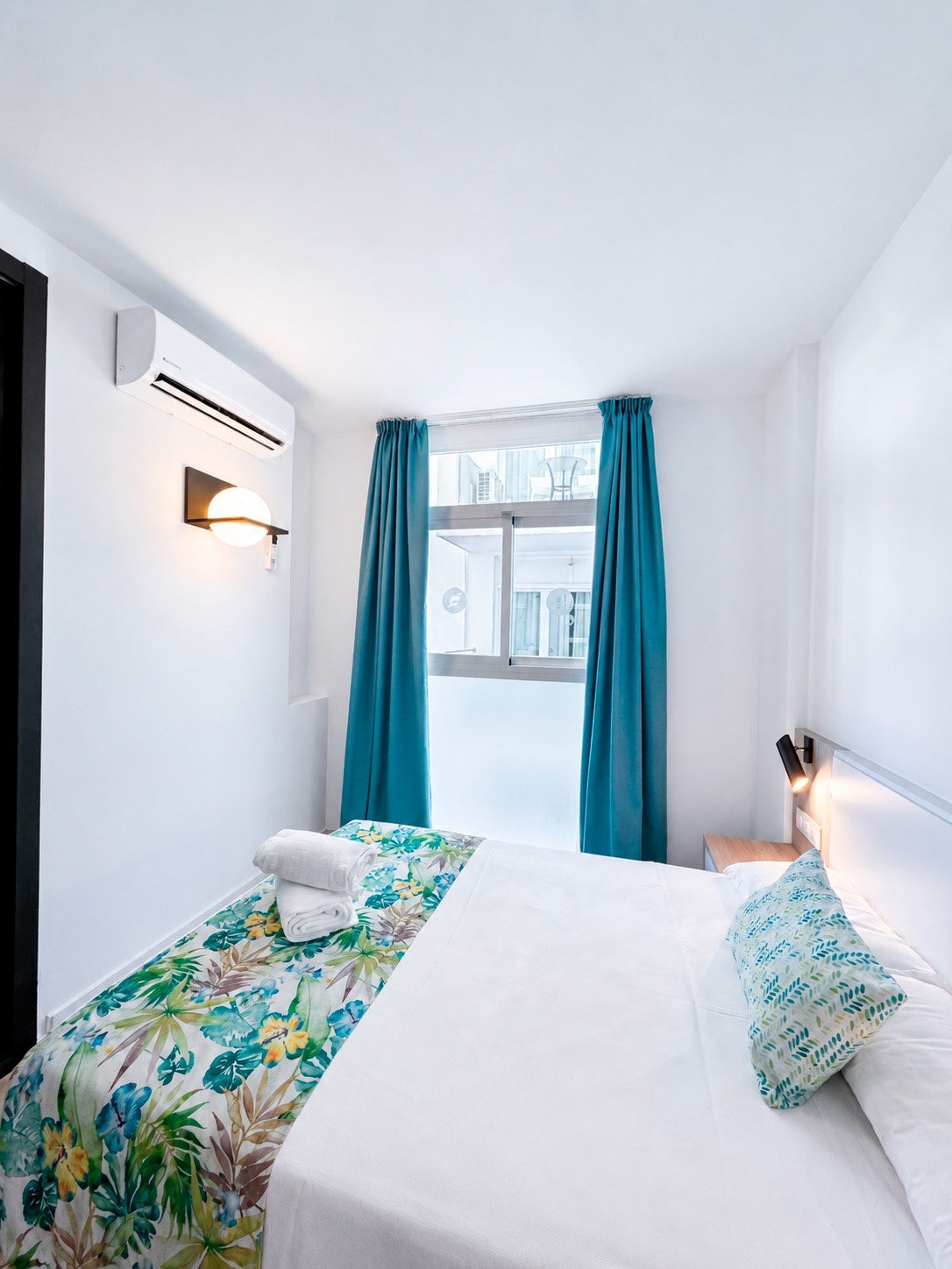 Dorobe: Hotel San Fermin - Cozy hotel room with bed, tropical runner, and bright window.