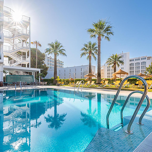 Hotel con piscina cristalina, palmeras y tumbonas bajo el sol, ideal para relajarse Dorobe: Hotel San Fermin.