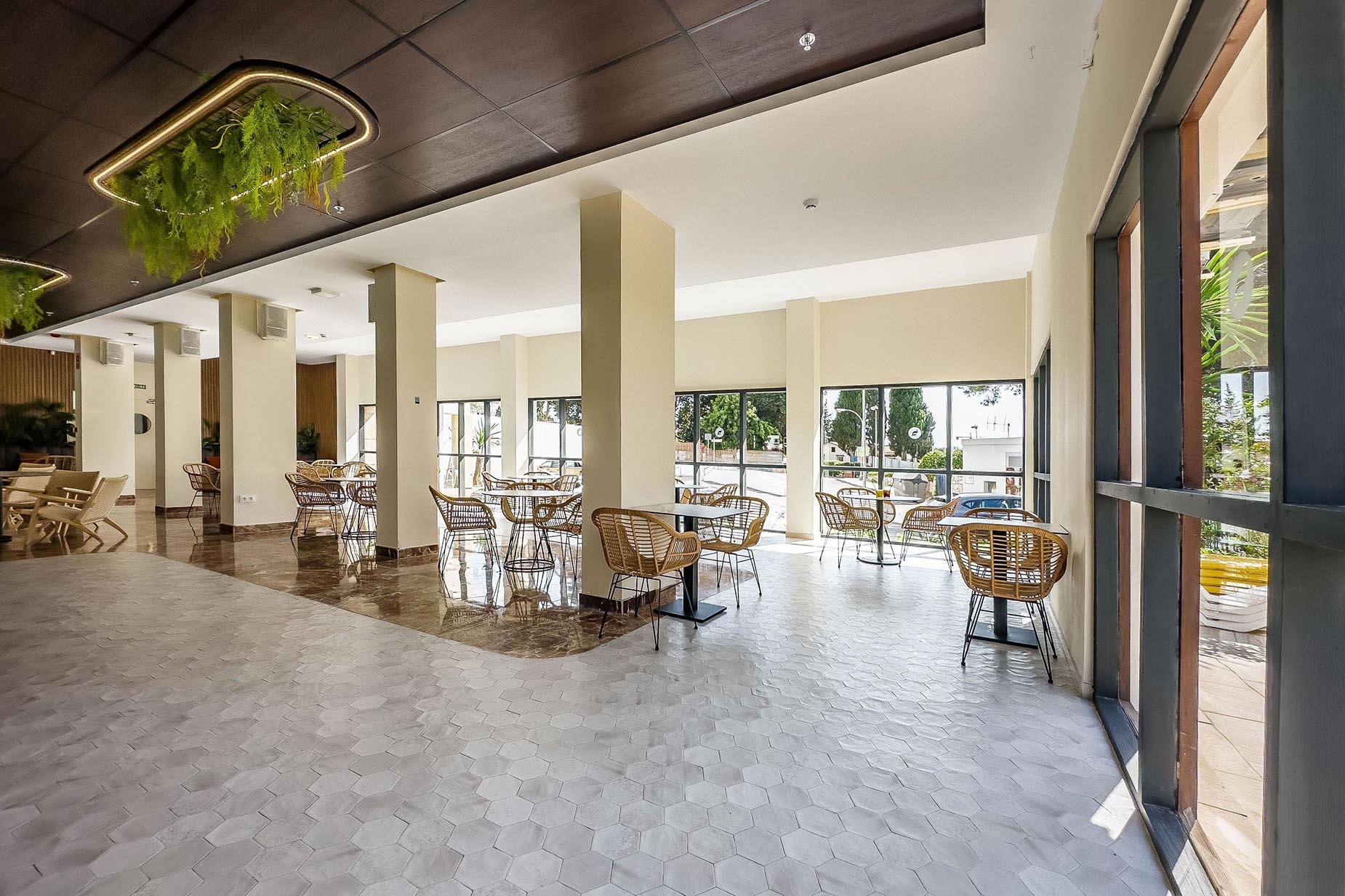 Dorobe: Hotel San Fermin, moderno salón comedor con mesas y sillas de ratán y vistas al exterior.