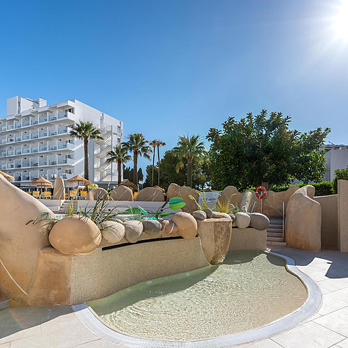 Resort con piscina infantil, palmeras y edificios blancos, ideal para familias con Dorobe: Hotel San Fermin.