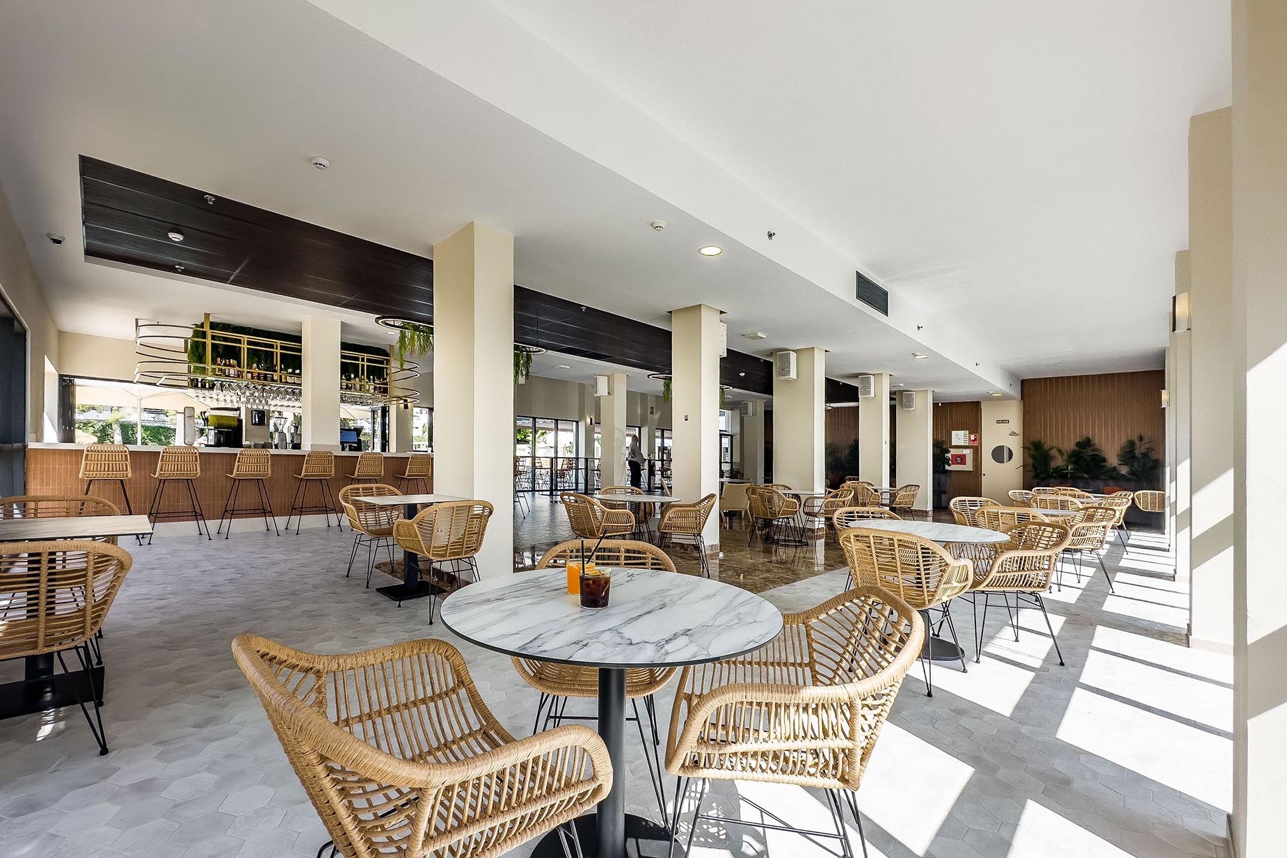 Dorobe: Hotel San Fermín, moderno salón con mesas y sillas de mimbre.