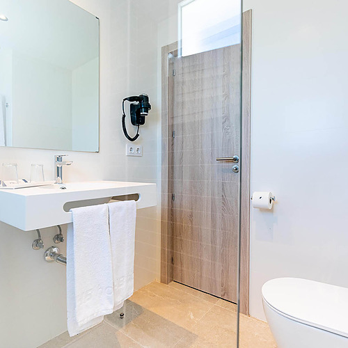 Baño moderno con lavabo, espejo, secador de pelo y WC. Dorobe: Hotel San Fermin