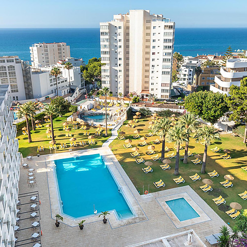 Vista aérea de piscinas, tumbonas y palmeras en un resort, perfecto para tu Dorobe: Hotel San Fermin.