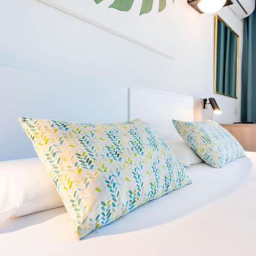 Almohadas decorativas en una cama blanca enDorobe: Hotel San Fermin.