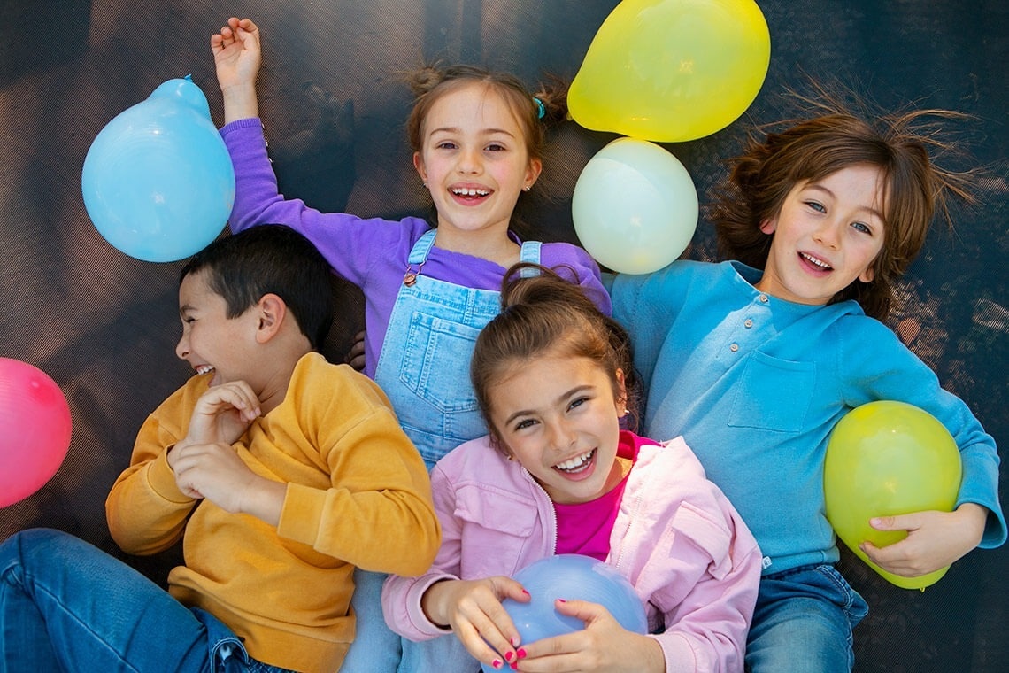 a group of children laying on the ground with balloons