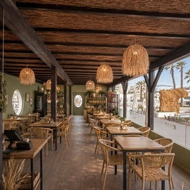 Mesas listas para cenar en Sands Beach, con sillas blancas y vista al mar.