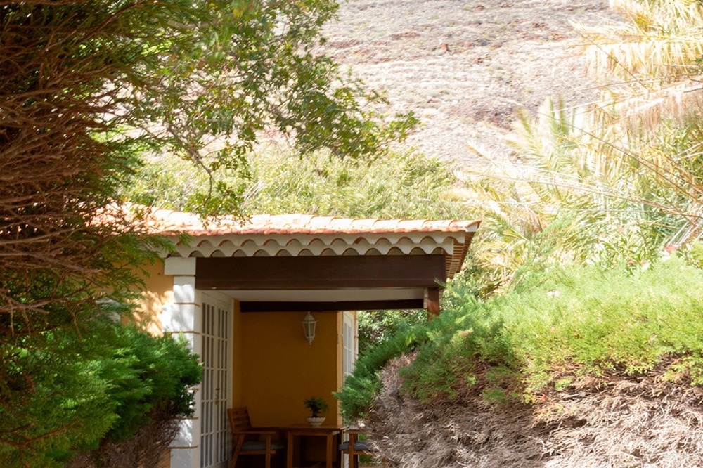 una casa blanca rodeada de flores rosas y arbustos