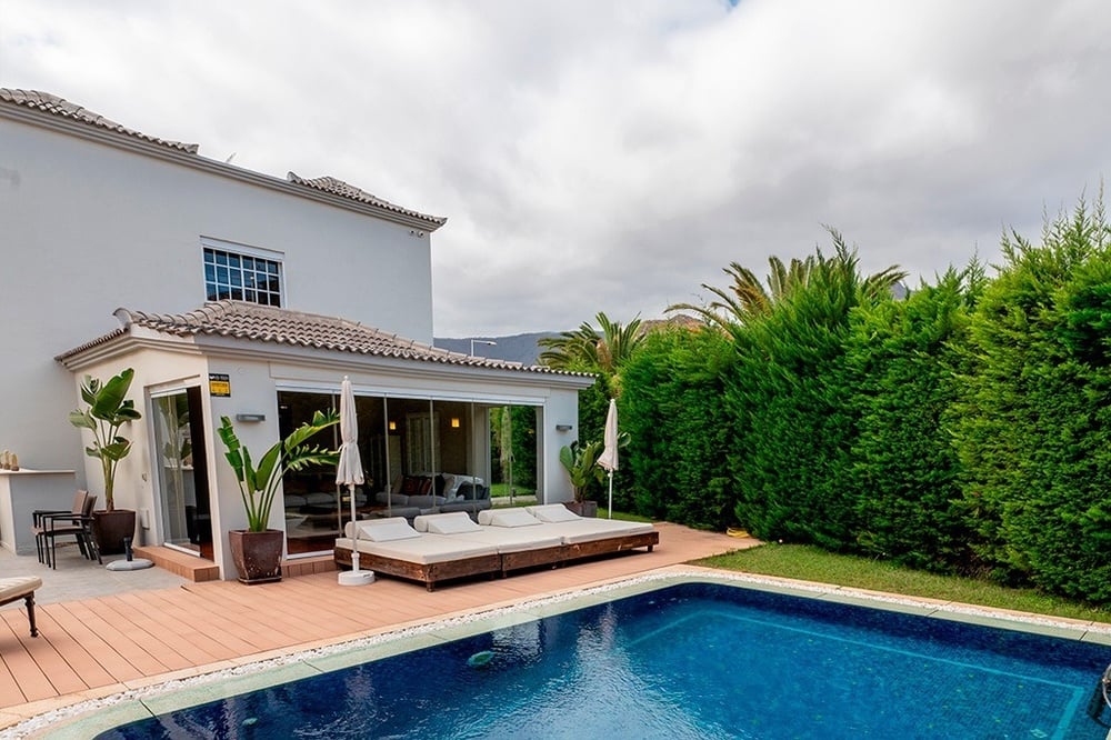 una gran piscina azul está rodeada de edificios blancos y palmeras .