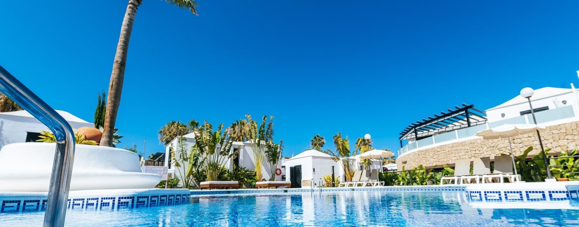 una piscina rodeada de edificios blancos y palmeras