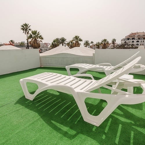 two white lounge chairs are sitting on a green carpet