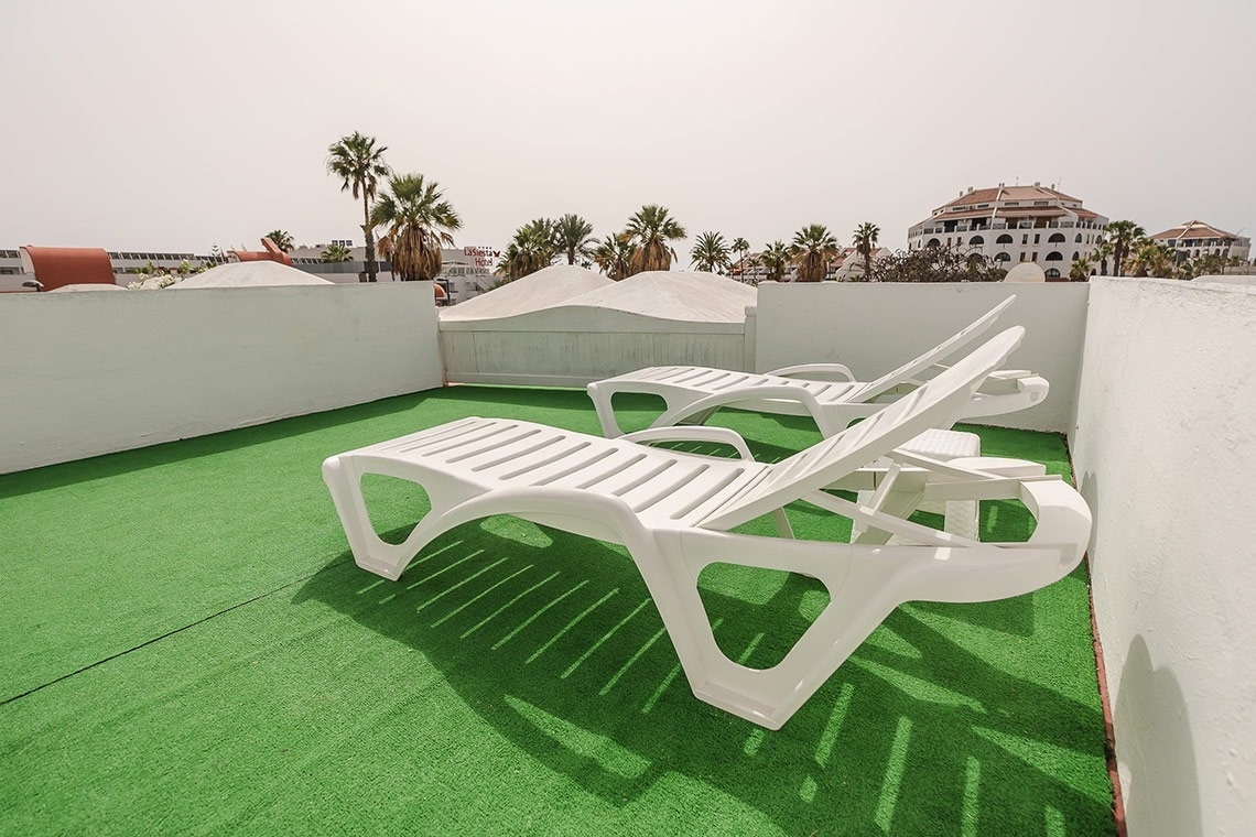 two white lounge chairs are sitting on a green carpet