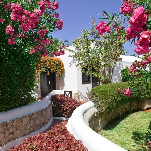 a white house with pink flowers in front of it
