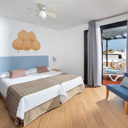 a hotel room with two beds and a blue chair