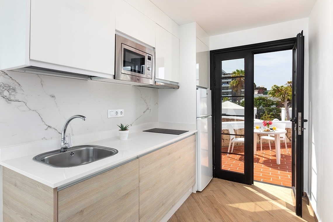 a kitchen with a sink a microwave and a sliding glass door
