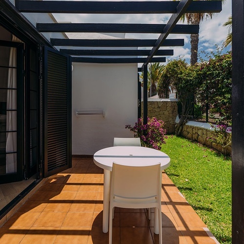 una mesa y sillas están sentados en un patio cubierto por una pérgola
